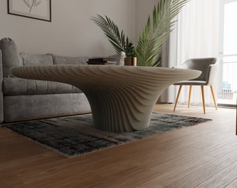 Peut inclure: Une table basse moderne et sculpturale de couleur blanche avec un design ondulé unique. La table est dans un salon avec un canapé gris et une plante en pot.