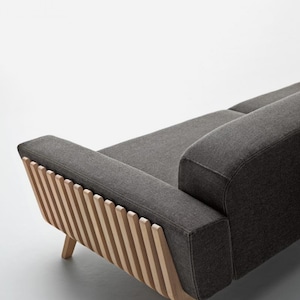 May include: A grey fabric sofa with a wooden frame. The frame has a unique design with vertical slats on the back.