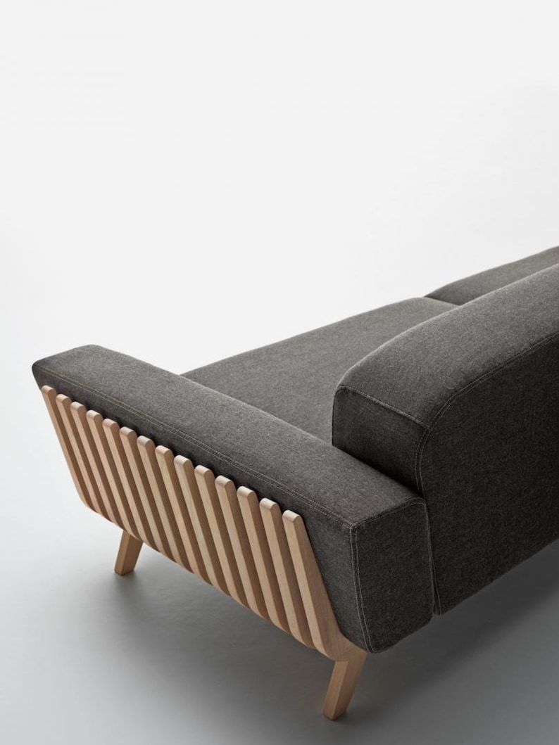 May include: A grey fabric sofa with a wooden frame. The frame has a unique design with vertical slats on the back.