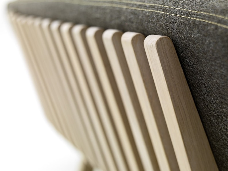 May include: Close-up of the back of a wooden chair with a grey fabric cushion. The chair has a slatted back with vertical wooden slats.