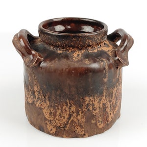 May include: A brown ceramic vase with two handles. The vase has a mottled brown and orange glaze with a textured surface.