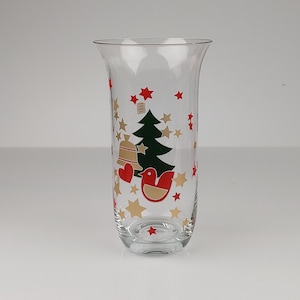Puede incluir: Un jarrón de vidrio transparente con un diseño de árbol de Navidad, pájaros y estrellas. El jarrón está decorado con detalles rojos, verdes y dorados.