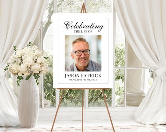 Könnte beinhalten: Ein weißes Gedenkschild mit schwarzem Text, der "Celebrating the Life of Jason Patrick 01.05.1967 - 13.03.2022" lautet. Ein Foto eines Mannes mit Brille befindet sich in der Mitte des Schildes.
