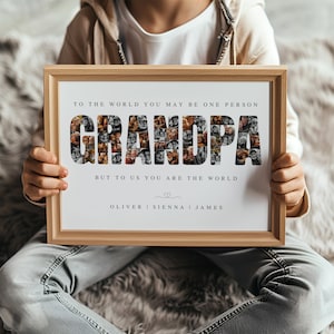 Op de afbeelding: Een houten fotolijst met het woord "GRANDPA" samengesteld uit kleine zwart-wit foto's. De tekst erboven luidt "TO THE WORLD YOU MAY BE ONE PERSON" en eronder "BUT TO US YOU ARE THE WORLD". Namen staan hieronder.