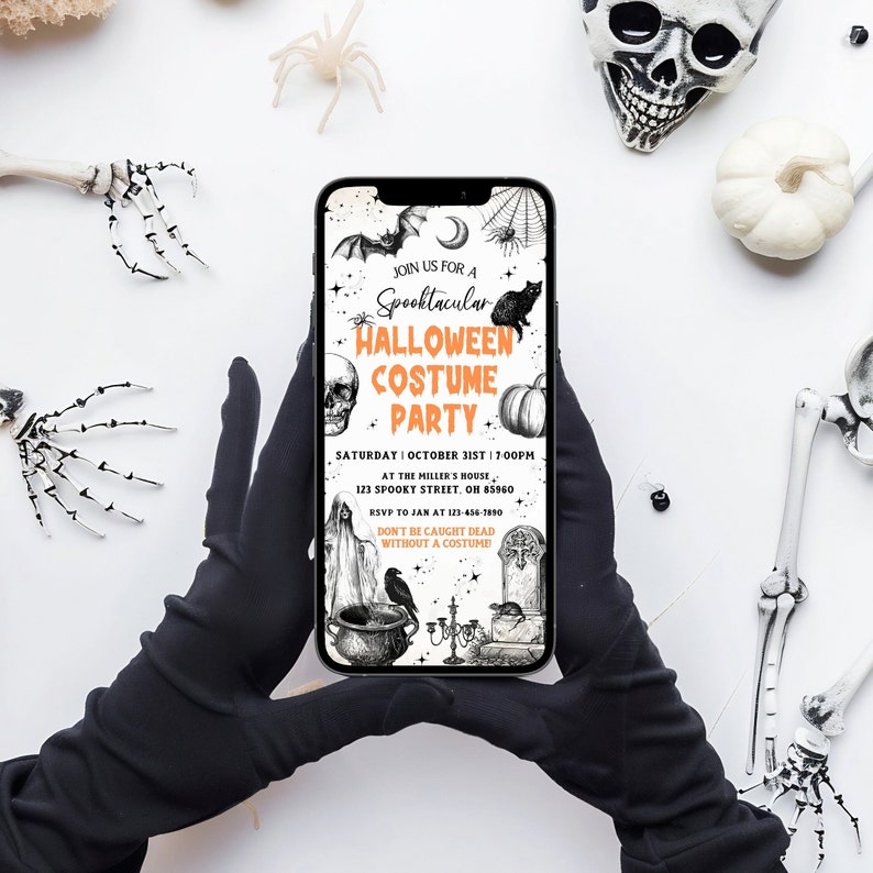 May include: A smartphone displays a Halloween Costume Party invitation. The invitation features a bat, spiderweb, black cat, skull, and pumpkin illustrations. The text reads "Join us for a Spooktacular Halloween Costume Party". The phone is held by gloved hands.