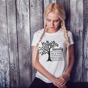 Pu&ograve; includere: Una maglietta bianca con un grafico di un albero nero e il testo "Family like branches on a tree we all grow in different directions yet our roots remain as one".