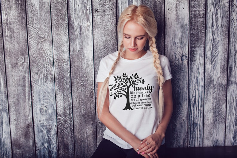 Pu&ograve; includere: Una maglietta bianca con un grafico di un albero nero e il testo "Family like branches on a tree we all grow in different directions yet our roots remain as one".