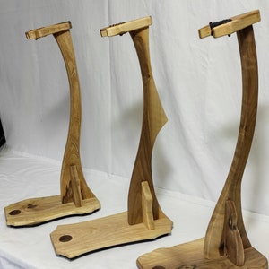 Pu&ograve; includere: Tre supporti per chitarra in legno con un design curvo. I supporti sono in legno marrone chiaro e hanno una finitura naturale.