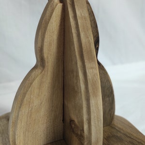 Pu&ograve; includere: Primo piano di un supporto in legno con un design curvo unico. Il supporto &egrave; in legno marrone chiaro e ha una finitura liscia e lucida.