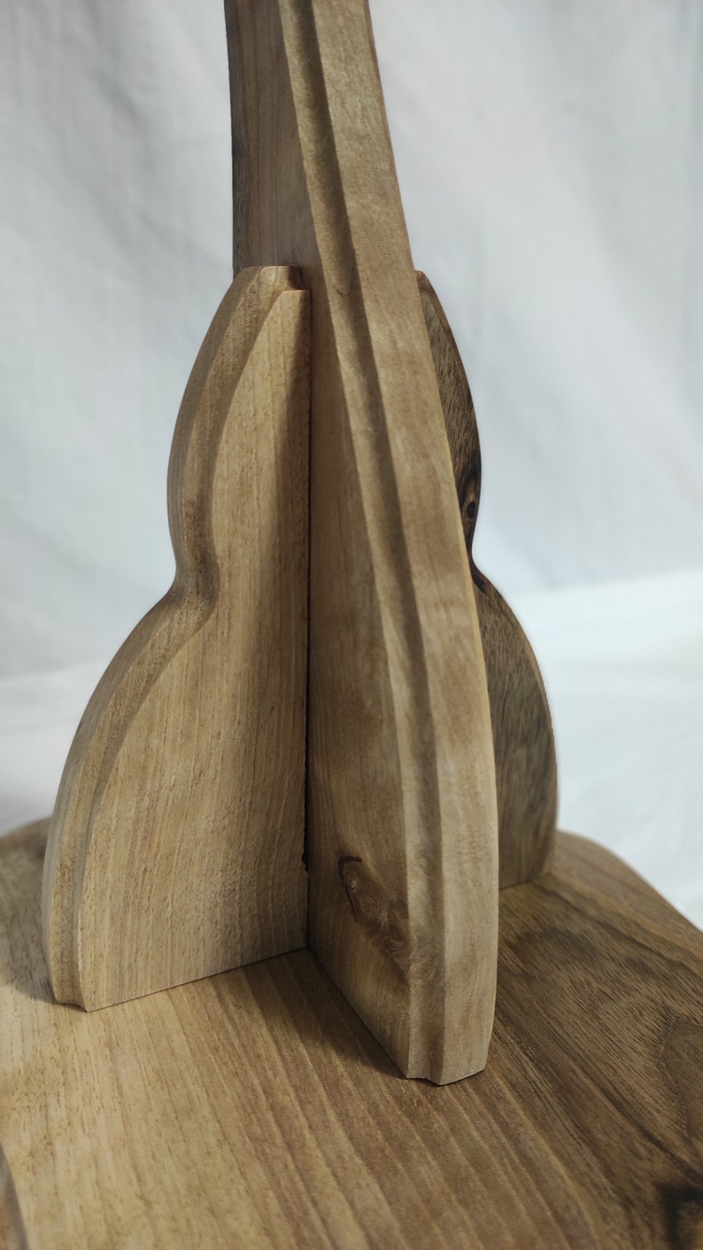 Pu&ograve; includere: Primo piano di un supporto in legno con un design curvo unico. Il supporto &egrave; in legno marrone chiaro e ha una finitura liscia e lucida.