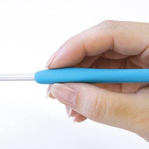 A hand holding a blue crochet hook, ready to crochet.