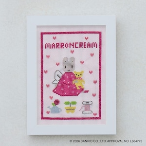 Könnte beinhalten: Ein gerahmtes Kreuzstichbild mit einem Cartoon-Kaninchen in einem rosa Kleid, das einen gelben Bären hält. Der Text "MARRONCREAM" steht oben. Weitere Elemente sind eine Gießkanne, eine Topfpflanze und eine Garnrolle. Der Hintergrund ist hellrosa.