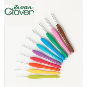 Puede incluir: Un conjunto de ganchillos con mangos coloridos en tonos amarillo, naranja, rojo, morado, azul, verde, rosa y marrón. Los ganchillos están dispuestos en forma de abanico, con la marca "Clover" visible en la esquina superior izquierda.