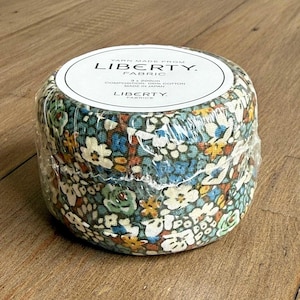 May include: A roll of Liberty Fabric, wrapped in clear plastic. The fabric has a floral pattern in shades of blue, green, white, and yellow. The label reads "Yarn Made From Liberty Fabric". The roll is 200cm in length and made of 100% cotton.