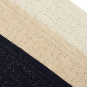 Puede incluir: Primer plano de tres muestras de tela en crema, beige y azul marino. Cada muestra presenta un patrón geométrico repetitivo de líneas discontinuas. Las telas están dispuestas en diagonal, mostrando sus diferentes colores y texturas.