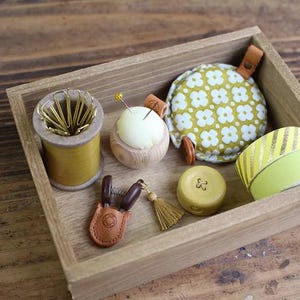 a wooden box filled with different types of sewing supplies