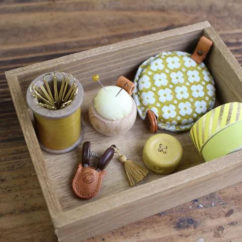a wooden box filled with different types of sewing supplies