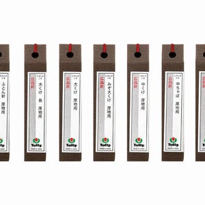 May include: Six packages of Tulip sewing needles. Each package is rectangular with a dark brown wood grain pattern and a red string. The packages have Japanese text and a white label with the Tulip logo.