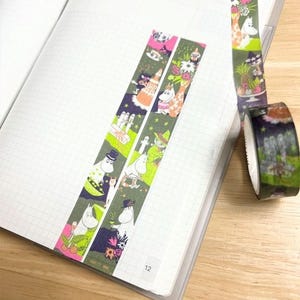 A notebook with a colorful, patterned tape on it, and a roll of tape lying next to it on a wooden surface.