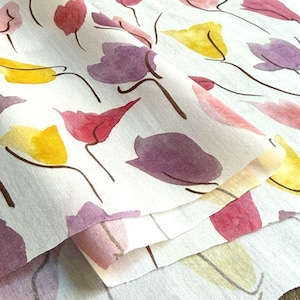 Peut inclure: Tissu blanc avec un motif floral à l'aquarelle. Le motif présente des fleurs stylisées dans des tons de rouge, de violet et de jaune, avec des tiges et des contours bruns. Le tissu est plié, montrant des couches du motif imprimé.