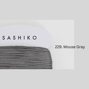 a close-up view of a spool of grey thread with the brand name "SASHIKO" printed on it.