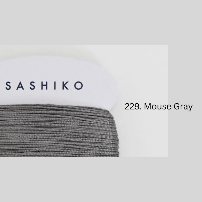 a close-up view of a spool of grey thread with the brand name "SASHIKO" printed on it.