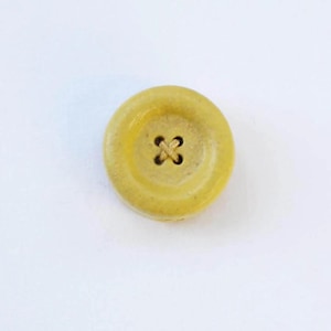 a yellow button with a four - leaf clover on it