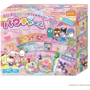 May include: A colorful Sanrio Characters craft kit with a pink and blue box. The box features illustrations of various Sanrio characters and instructions. The kit includes materials to create charms, with the text "15 charms" and "USB power" visible.