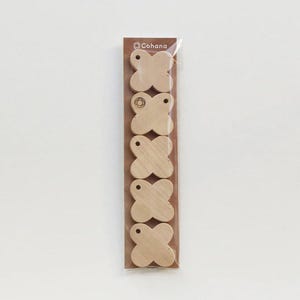 Puede incluir: Un paquete de seis carretes de hilo de coser de madera con forma de trébol. Cada carrete tiene un pequeño agujero en la parte superior y está hecho de madera de color claro. El paquete tiene el nombre de la marca "Cohana" impreso en la parte superior.