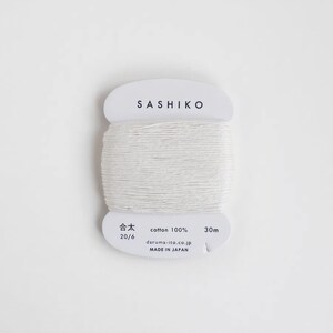 A spool of white thread labeled "SASHIKO" against a white background.