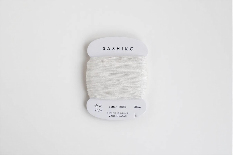 A spool of white thread labeled "SASHIKO" against a white background.