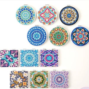 May include: A collection of eleven diamond painting coasters featuring circular and square shapes. Each piece displays intricate, colorful mandala and floral patterns created with faceted, reflective gems in shades of blue, pink, green, and gold.