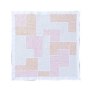 May include: A square white textile featuring a geometric pattern composed of small, embroidered dash stitches. The design consists of alternating rectangular blocks in shades of light pink, soft orange, and pale grey, arranged in a grid-like layout.