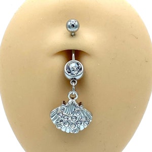 Può includere: Un piercing per l'ombelico in argento con un cristallo trasparente e un ciondolo a forma di conchiglia con cristalli trasparenti.
