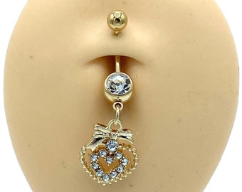 May include: Gold belly button ring with a clear gem and a dangling heart charm with a bow and rhinestones.