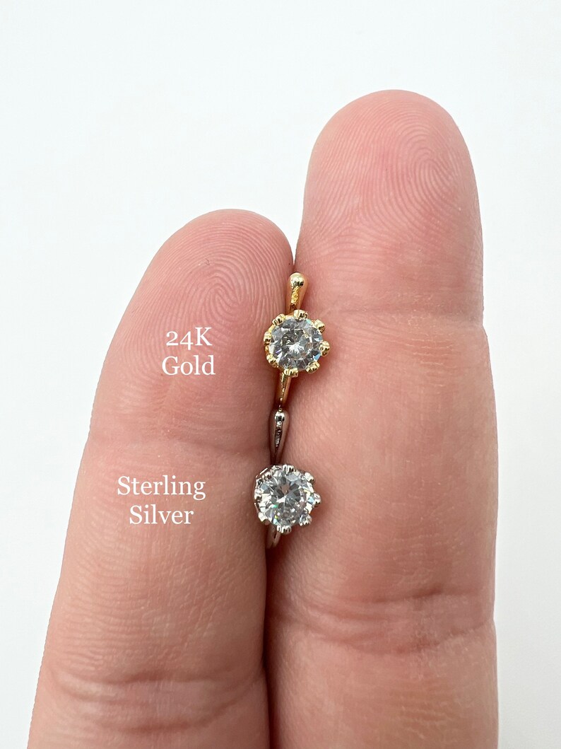 Puede incluir: Dos anillos de nariz con una piedra preciosa transparente. El anillo de la izquierda est&aacute; hecho de oro de 24 quilates y el anillo de la derecha est&aacute; hecho de plata de ley.