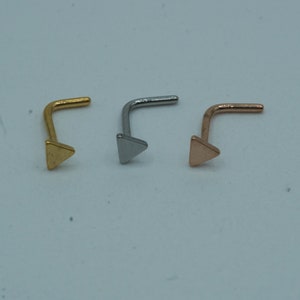 May include: Three nose rings with triangle-shaped ends. The rings are gold, silver, and rose gold.