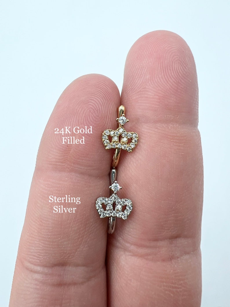 May include: Two nose rings with a crown design. The top ring is 24K gold filled and the bottom ring is sterling silver.