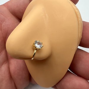 Puede incluir: Un aro de nariz de oro con una piedra redonda transparente.