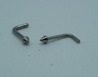 May include: Two silver nose rings with a pointed tip. The rings are bent at a 90-degree angle.