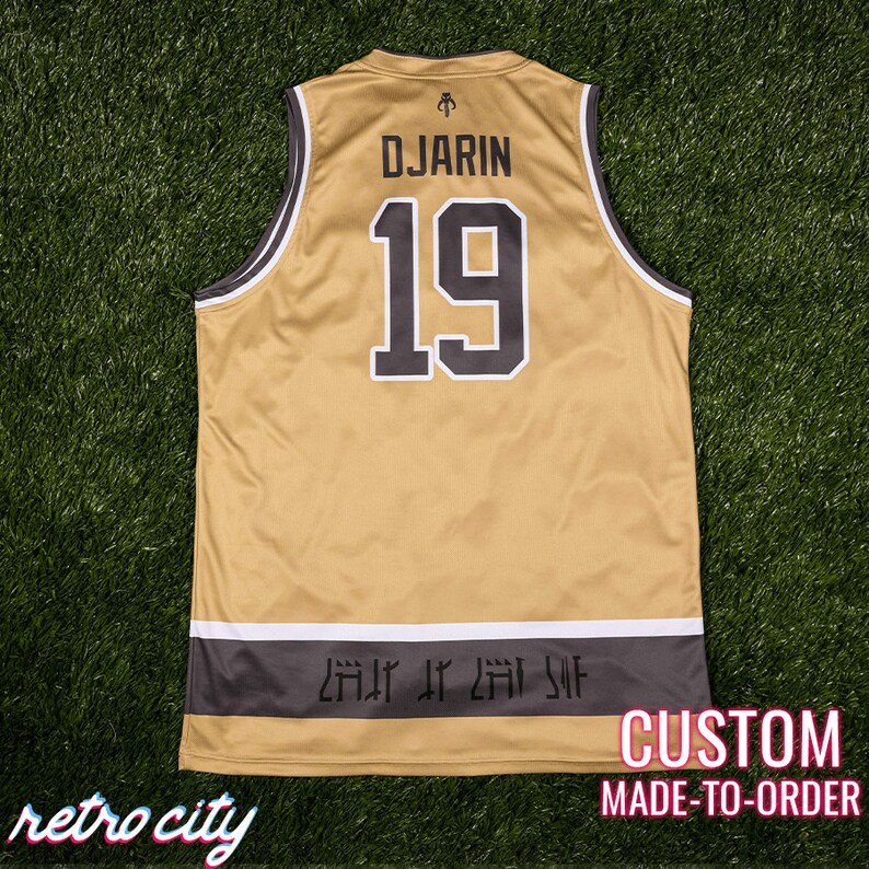 May include: Gold and black custom-made jersey with the name "DJARIN" and the number "19" on the back. The jersey has a white and black trim and a dark gray band at the bottom with stylized text. The words "retro city" are at the bottom left.