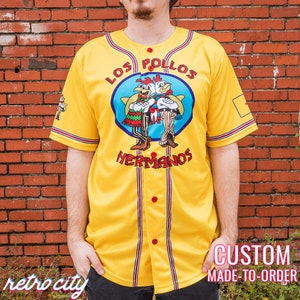 May include: Yellow baseball jersey with red and blue accents. The jersey features the text "LOS POLLOS HERMANOS" above a cartoon image of two chickens. The jersey also has the text "retro city" and "CUSTOM MADE-TO-ORDER".