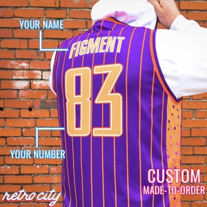 May include: Purple and orange basketball jersey with white stripes. The jersey has the text "FIGMENT" and the number "83" on the back. The text "CUSTOM MADE-TO-ORDER" is at the bottom of the jersey. The text "YOUR NAME" and "YOUR NUMBER" are written on the left side of the jersey.