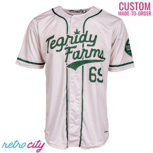 Peut inclure: Maillot de baseball blanc avec des bordures vertes et le texte "Tegridy Farms" en écriture cursive verte. Le numéro "65" est imprimé en vert sous le texte.