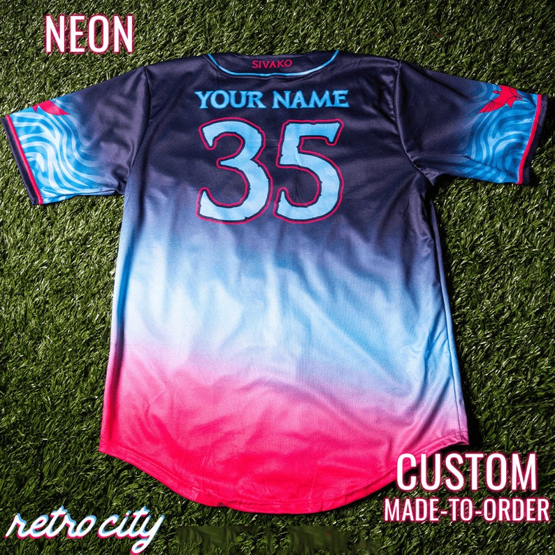 May include: A black, blue and pink baseball jersey with a gradient design. The back of the jersey has the text "YOUR NAME" and the number "35" in white with a blue outline. The text "SIVAKO" is on the back of the collar. The jersey has a custom made-to-order design.