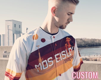 May include: A white baseball jersey with a retro design featuring orange, yellow and red stripes. The jersey has the text "Mos Eisley Tatooine" printed on the front. The jersey is custom made to order.