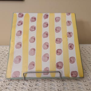 May include: A square ceramic serving tray with a yellow and white striped pattern and pink polka dots.