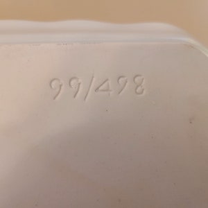 Puede incluir: Primer plano de un objeto de cer&aacute;mica blanca con el n&uacute;mero "99/498" impreso en &eacute;l.
