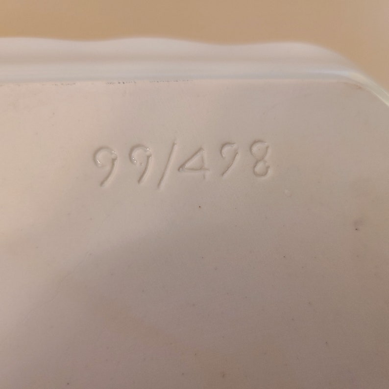Puede incluir: Primer plano de un objeto de cer&aacute;mica blanca con el n&uacute;mero "99/498" impreso en &eacute;l.