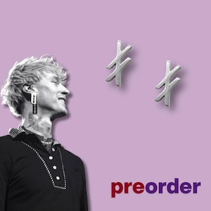 Puede incluir: Dos pendientes plateados con forma de X estilizada. Los pendientes se muestran sobre un fondo lavanda. La palabra "preorder" está escrita en texto rojo y morado en la parte inferior de la imagen.